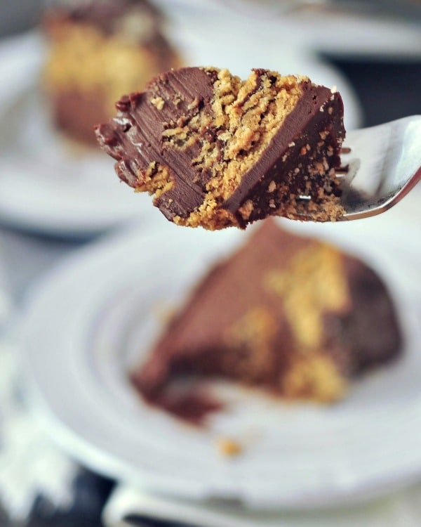 a bite of chocolate biscuit cake on a fork, with two full cake slices on plates in blurred background