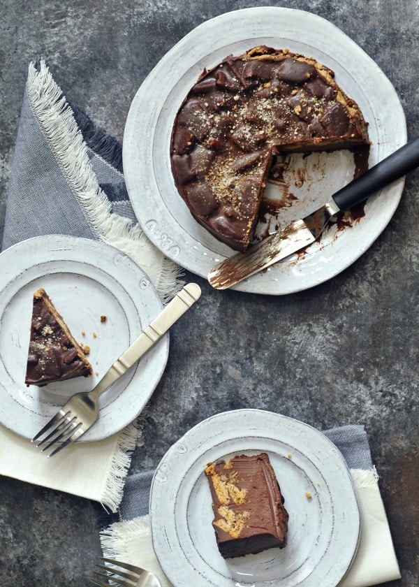 overhead view of two slices of chocolate biscuit cake on plates, full cake on larger serving plate next to them.