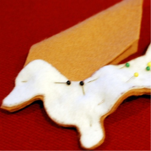 A felt dachshund pinned together to sew.