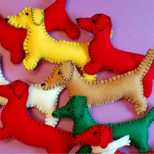 A pile of colorful handmade felt dachshund ornaments, ready to hang on the tree!