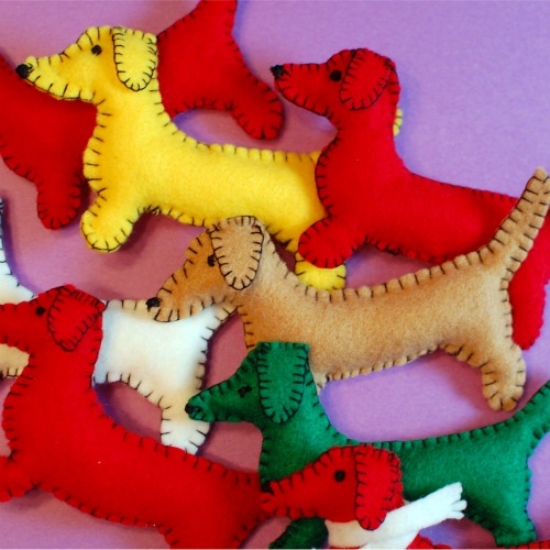 A pile of colorful handmade felt dachshund ornaments, ready to hang on the tree!