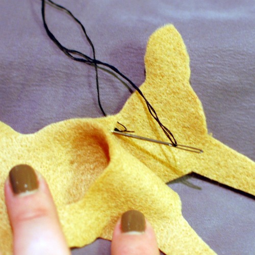 Hand sewing a blanket stitch around two dachshund shaped pieces of felt.