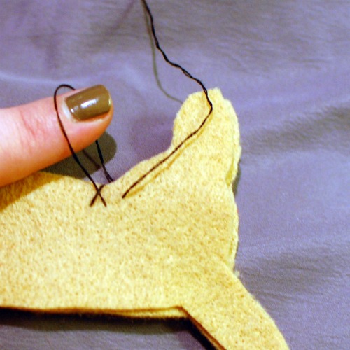 Hand sewing a blanket stitch around two dachshund shaped pieces of felt.