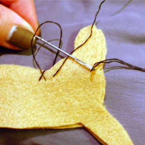 Hand sewing a blanket stitch around two dachshund shaped pieces of felt.