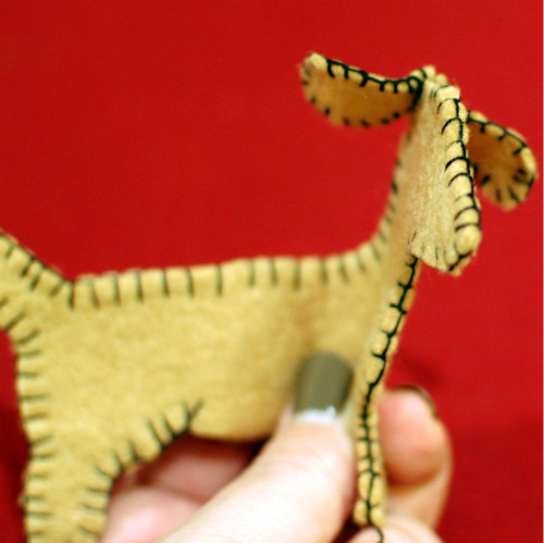 A handmade dachshund shaped ornament, fully sewn except for the final one inch space left open to fill ornament with stuffing.