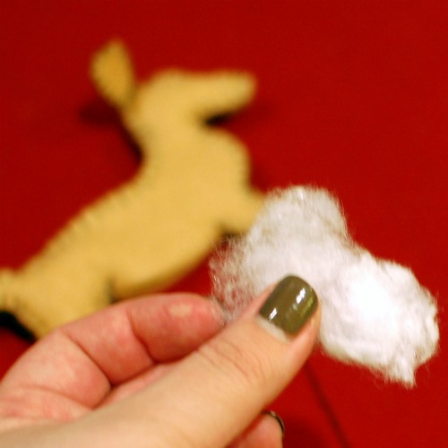 Handmade felt dachshund ornament being filled with white fluffy stuffing.