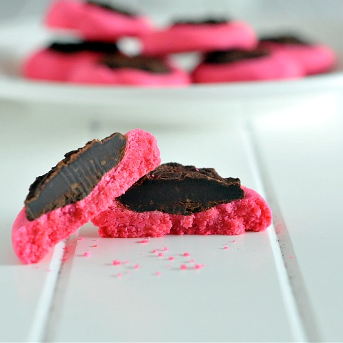Pink Thumbprints with Whiskey Ganache on a plate, one sliced in half in front of plate