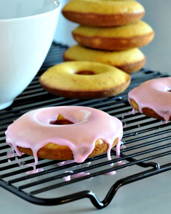 pink iced saffron donuts on a baking rack, bowl of pink rosewater icing on the side