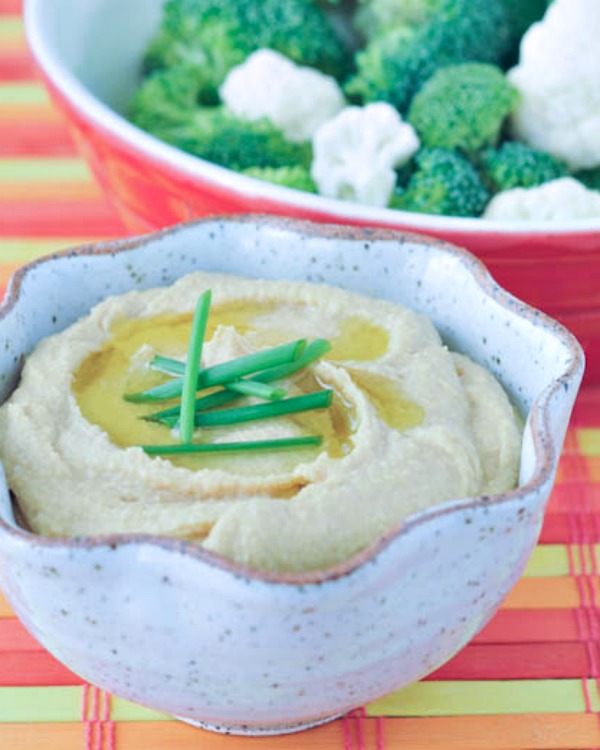 Bright Lemon Miso Hummus in a bowl with broccoli and cauliflower for dipping