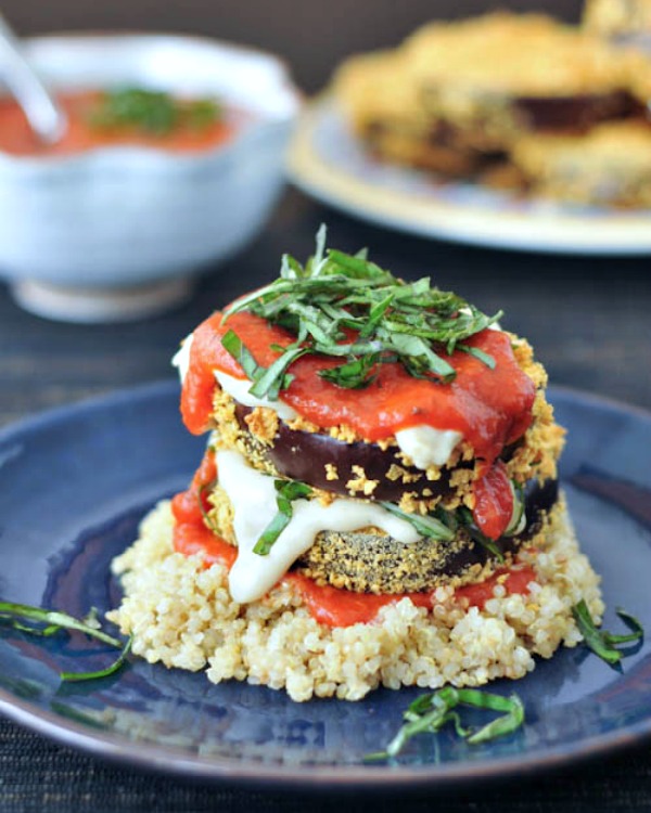 two slices of crispy eggplant stacked on top of quinoa and covered with marinara sauce and fresh chopped basil leaves.