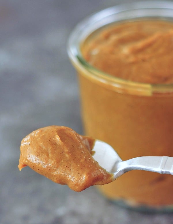 a spoonful of Vegan Caramel Sauce, jar of caramel in background