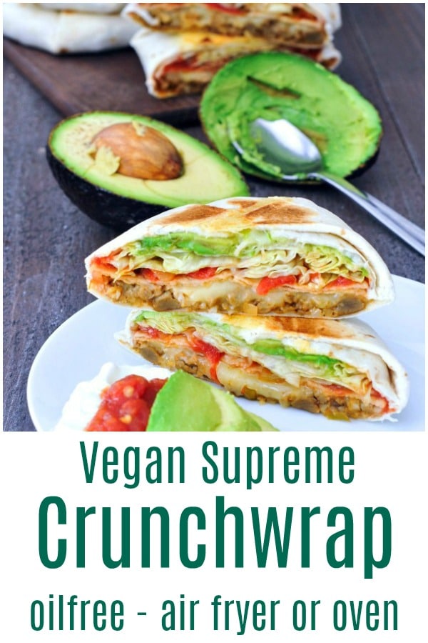 Vegan crunchwrap supreme sliced in half on a plate, fresh avocado with spoon and half avocado scooped out