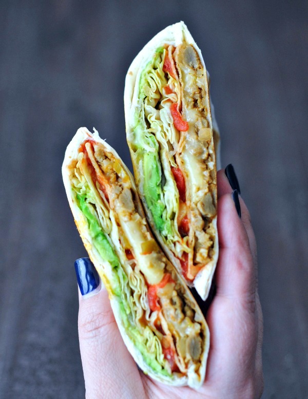 vegan crunchwrap sliced in half and held in a hand