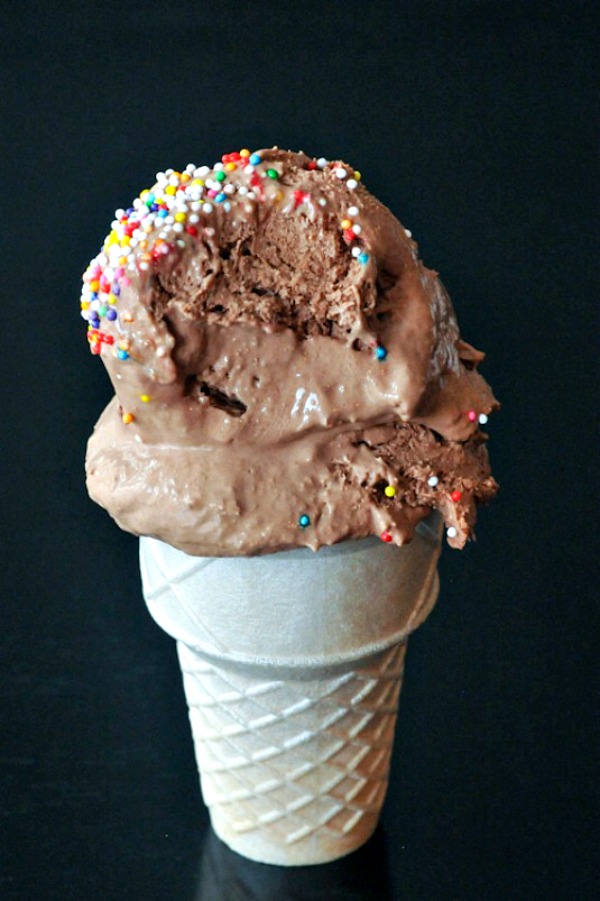 two scoops of Chocolate Oat Milk Ice Cream with sprinkles in a cone against a black background
