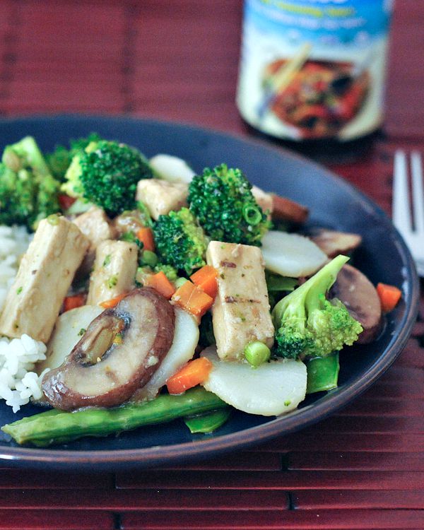 a blue plate of Moo Goo Gai Pan: sautéed vegan protein, sliced carrots, snap peas, broccoli trees over rice