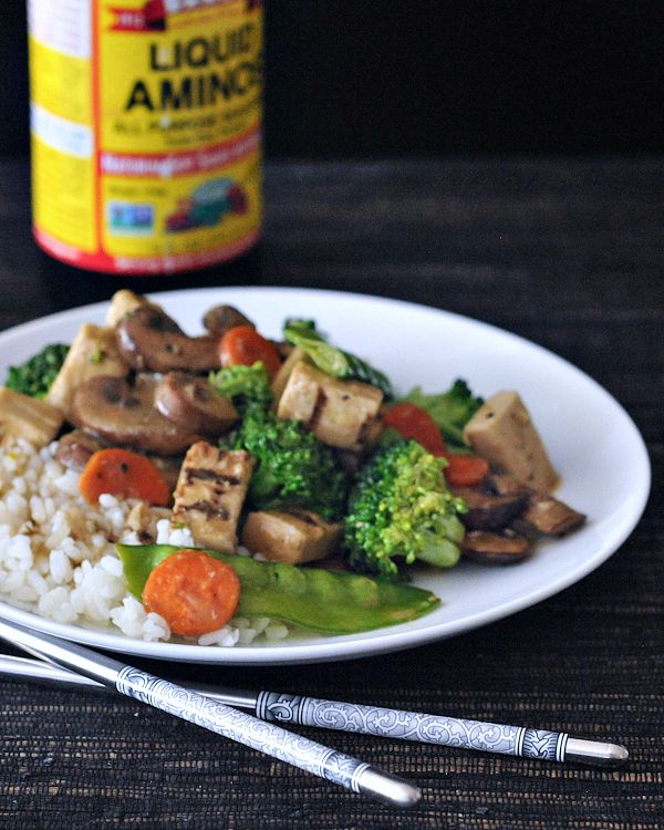 a white plate of Moo Goo Gai Pan: sautéed vegan protein, sliced carrots, snap peas, broccoli trees over rice