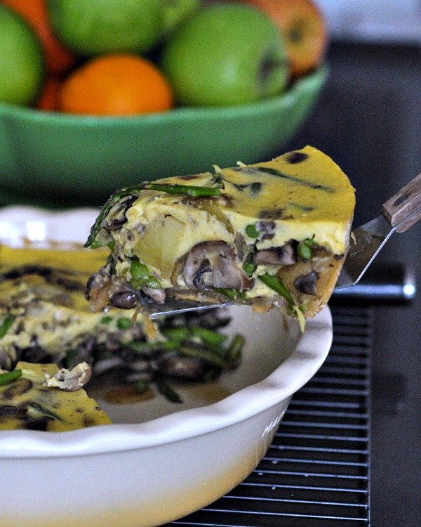 one slice of vegan mushroom quiche on a small spatula, being lifted from pie dish.