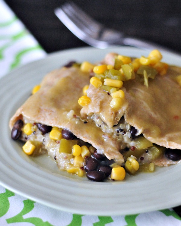 close up view of quinoa black bean and corn enchiladas on a grey plate.