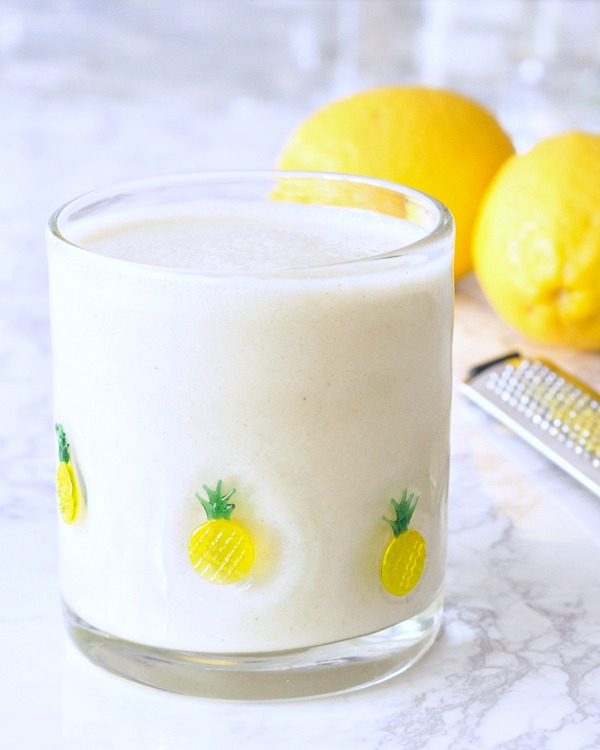 lemon smoothie in a glass, whole lemons in background