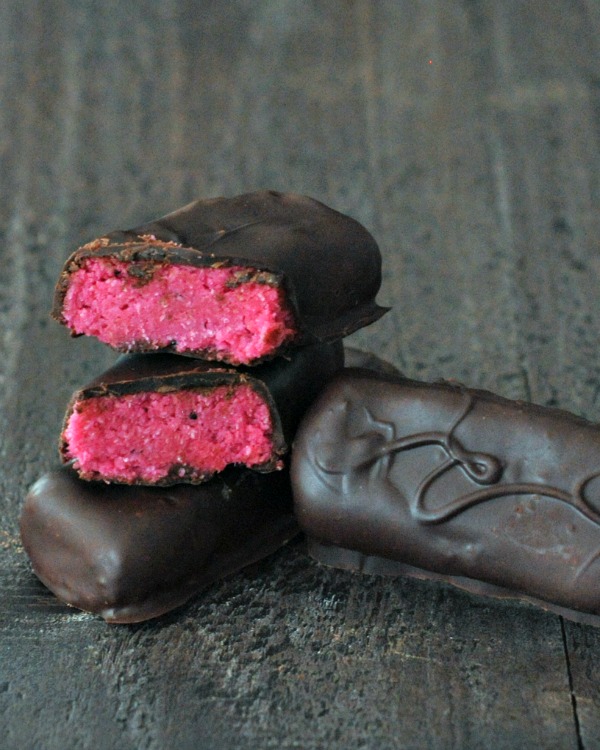 Dark Chocolate Dragon Fruit Coconut Treats sliced in half so to show pink middle