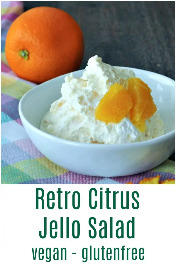 serving of Jello Salad in a white bowl, pastel plaid napkin and full orange fruit in background