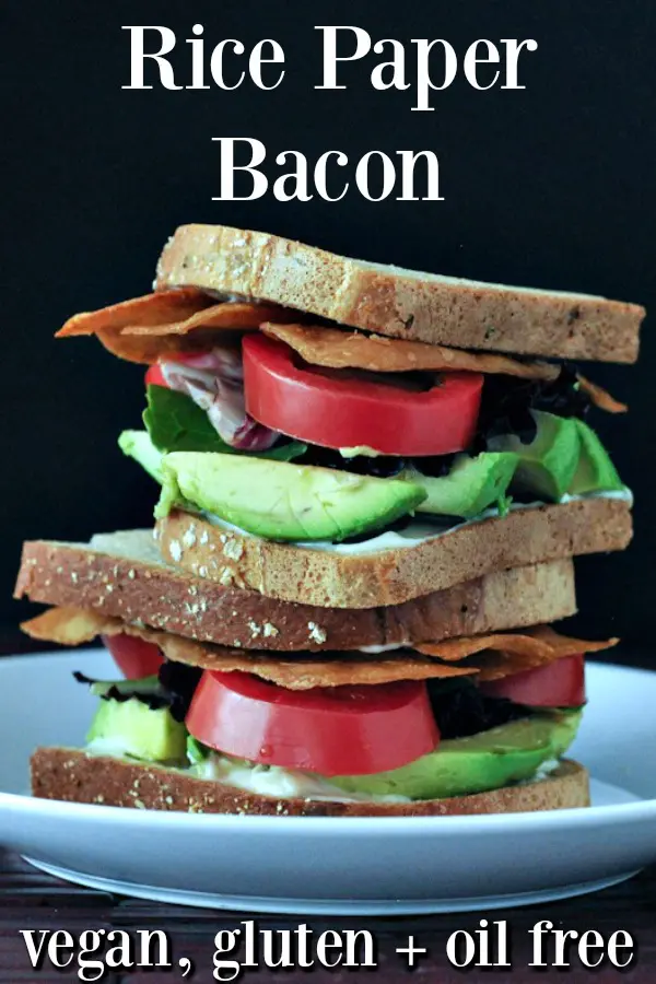 Vegan Rice Paper Bacon as part of a BLT sandwich - bread, green avocado, red tomato, bacon stacked high against a black background