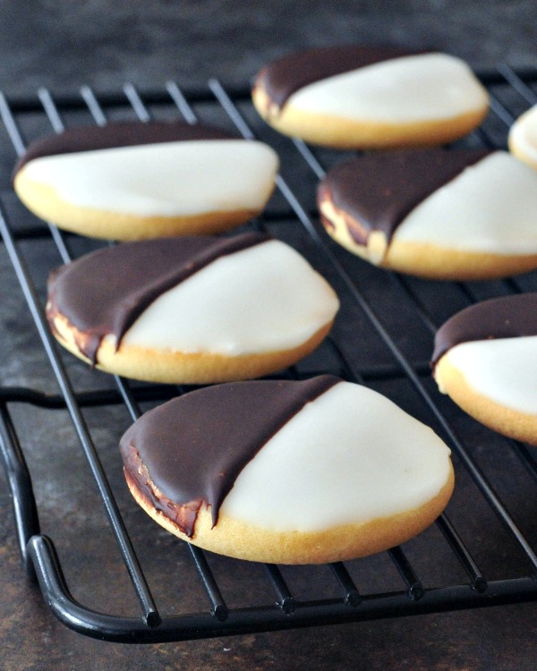 Black and White Cookies on a cooling rack. black and white cookie is a cake like vanilla cookie with half chocolate frosting and half white frosting.