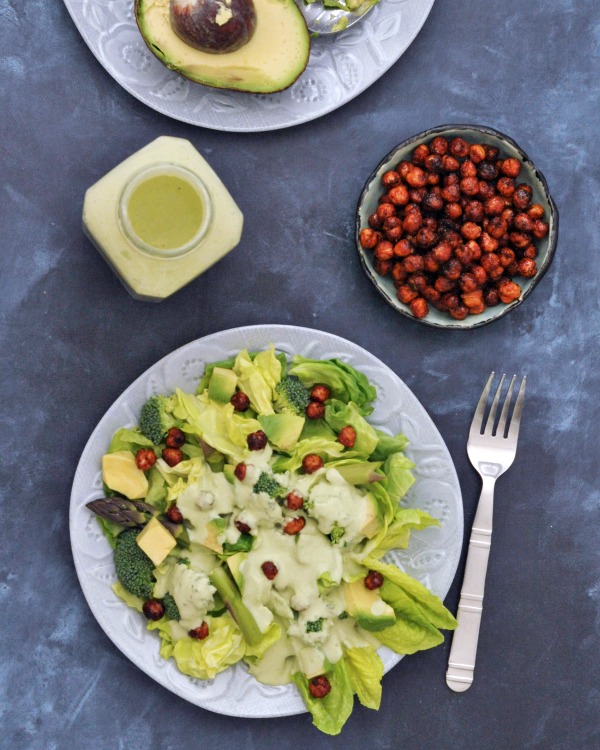 overhead view of Hearty Nourishing Greens Salad Recipe: butter lettuce, avocado, asparagus, crunchy chickpeas on a plate with a fork on the side, extra crunchy chickpeas on the side