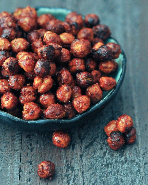 A bowl of air fried smoky sweet chickpeas sits on a wooden table.