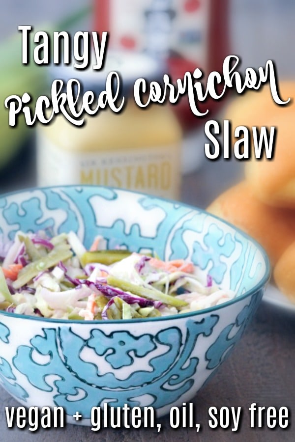 Tangy Pickled Cornichon Slaw - oil free slaw recipe in a serving bowl with BBQ items in background: hot dog buns, mustard jar, ketchup bottle