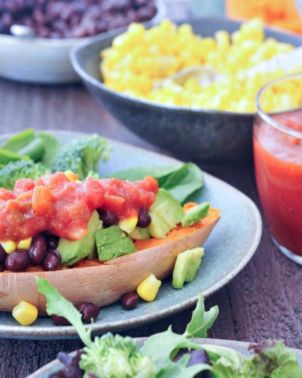 Savory Sweet Potato Breakfast Boats on a plate with corn and beans in bowls in background