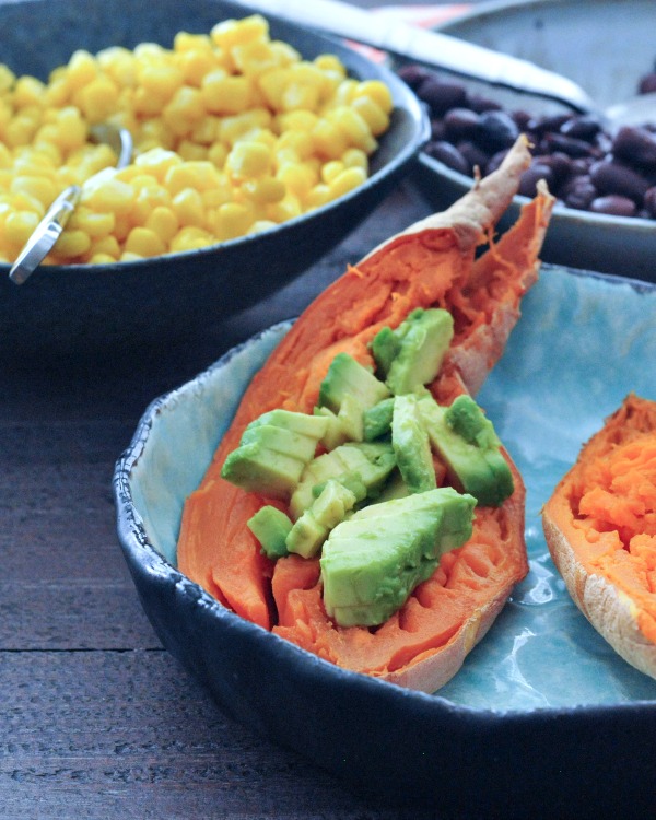Savory Sweet Potato Breakfast Boats Recipe filled with avocado, corn in bowl in background