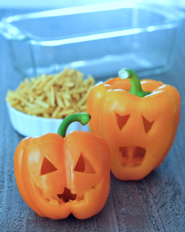 two orange bell peppers carved into a halloween jack o lanterns