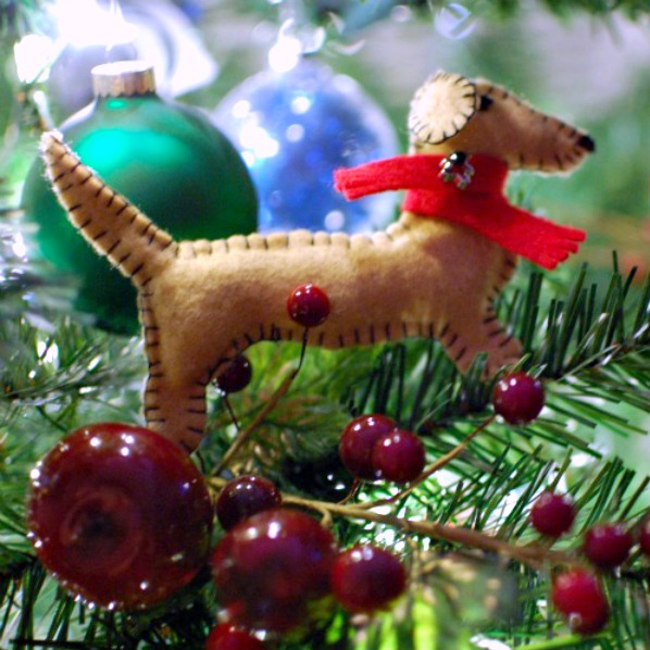 A felt sewn dachshund ornament hanging on a Christmas tree.