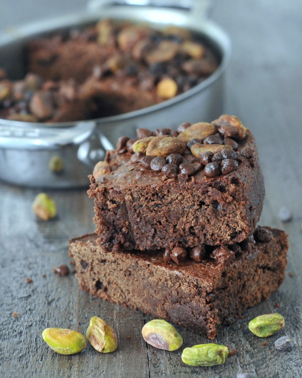 stack of air fryer brownies, pan in the background, pistachios scattered about