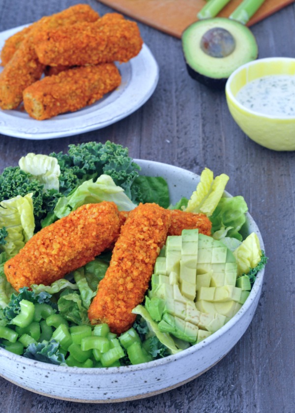 Vegan Buffalo Wing Salad in a bowl, extra wings, avocado, and dressing on the side