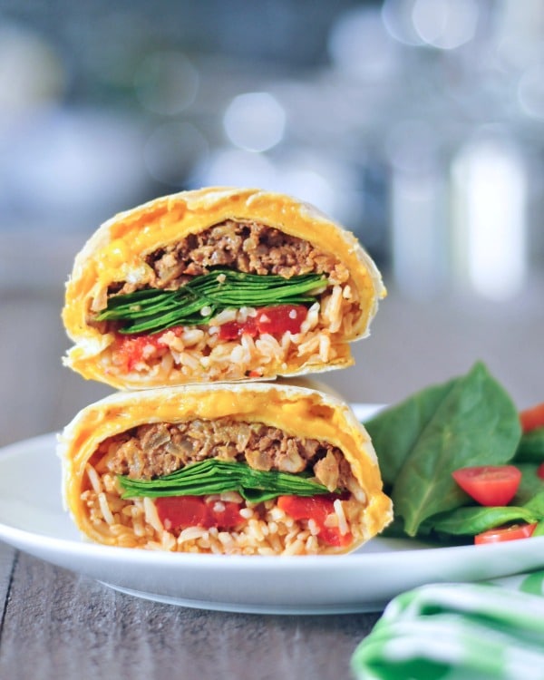a cheesy quesarito sliced in half and stacked to show insides - rice, beans, spinach, and tomato salsa wrapped in a cheese layer of quesadilla.