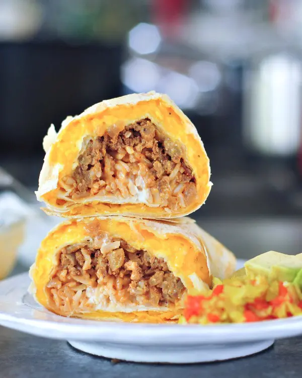 a cheesy quesarito sliced in half and stacked to show insides - rice, beans, and tomato salsa wrapped in a cheese layer of quesadilla.