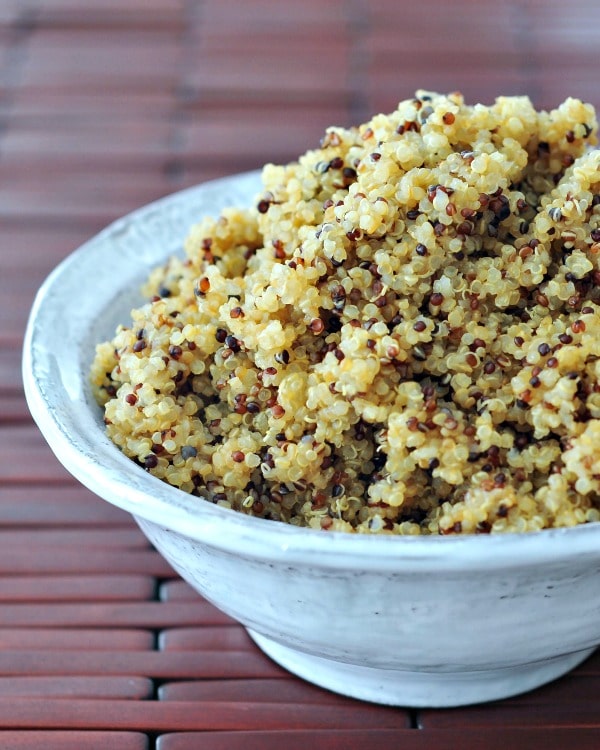cooked quinoa piled into a white rustic bowl.
