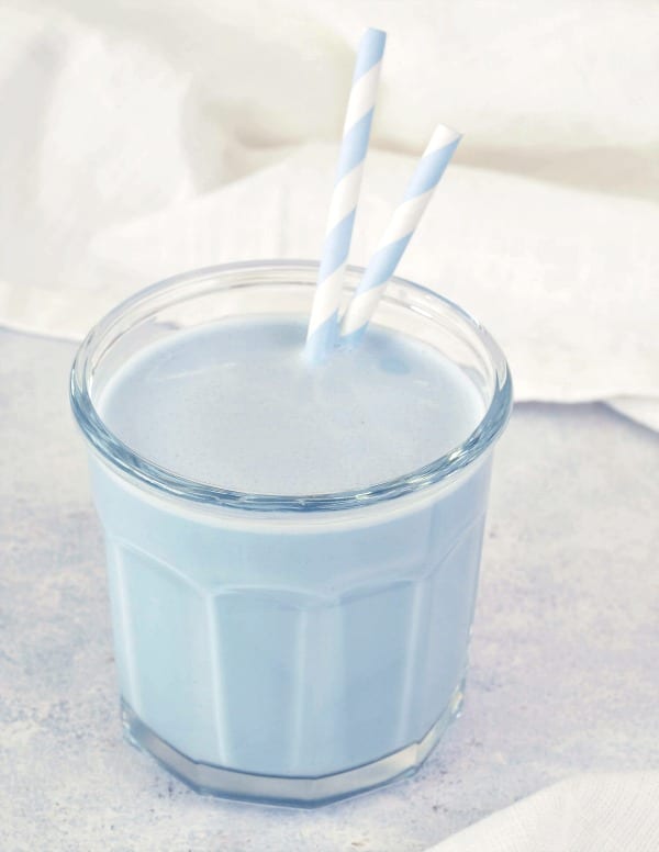 pale blue vanilla mint cashew milk in a clear glass with blue and white striped paper straws