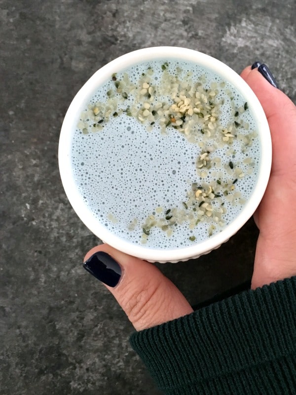 overhead view of pale blue vanilla mint cashew milk in a white mug, garnished with hemp seeds