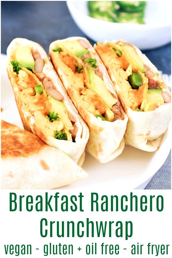 Two ranchero style breakfast crunchwraps sliced in half and arrranged on a white dish. Crunchwrap is filled with scrambled egg, beans, ranchero sauce, jalapenos.