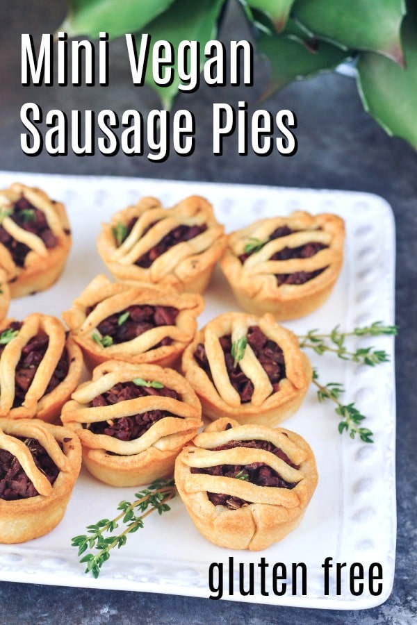 Mini vegan sausage pies on a white square platter dressed with sprigs of fresh thyme.