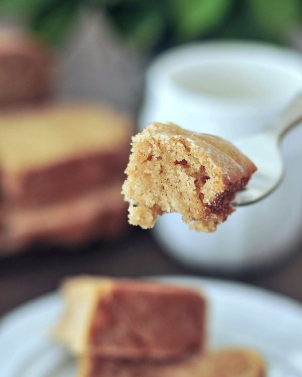 one bite of snickerdoodle bread on a fork, rest of slice on a plate in blurred background