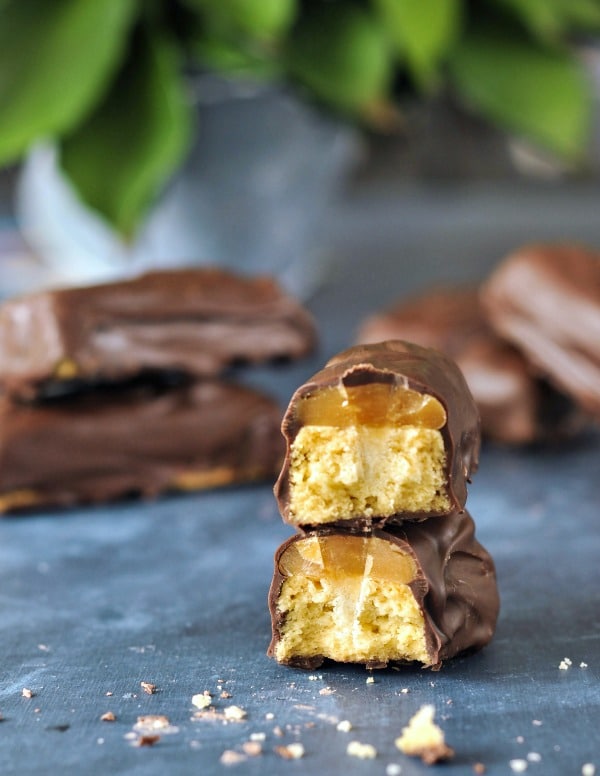 a homemade vegan Twix candy bar broken in half to see the caramel and cookie inside.
