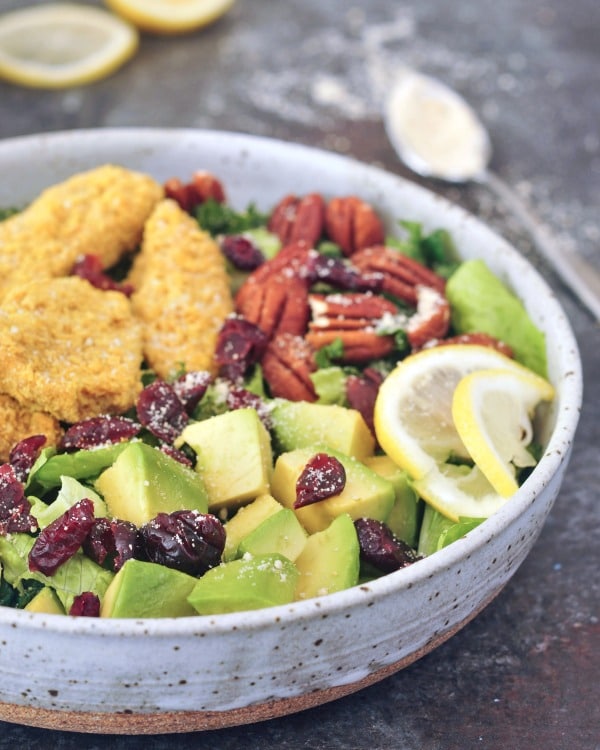 close up view of Cranberry Chicken Salad in a rustic grey bowl, and lemon slices on the side