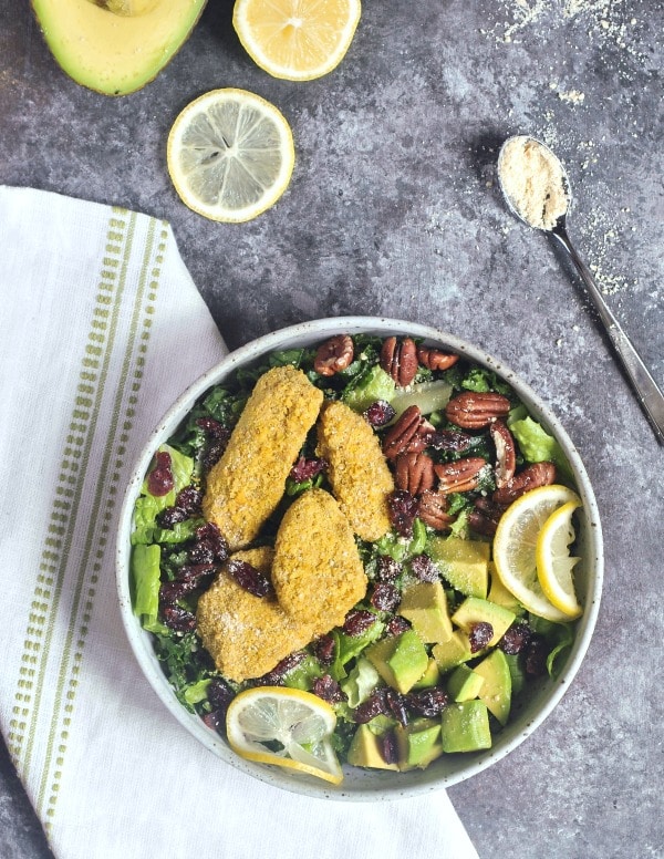 Vegan Cranberry Chicken Salad in a rustic grey bowl, half an avocado and lemon slices on the side