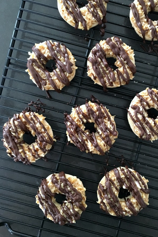 overhead view of Samoa Girl Scout Cookies (shortbread with coconut caramel and a chocolate drizzle) drying on a black cooling rack.