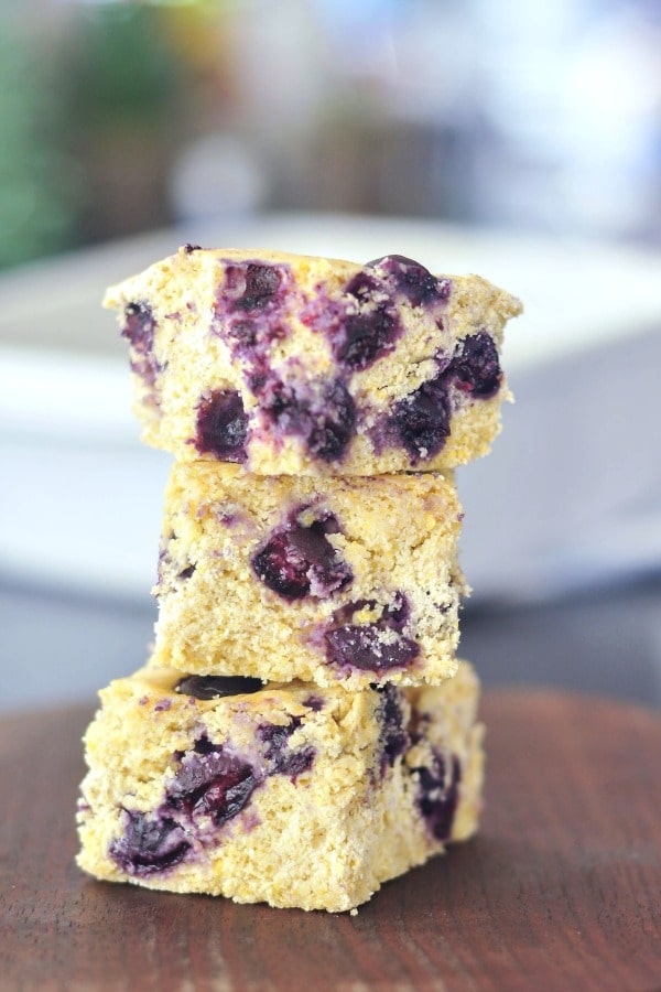 a stack of blueberry cornbread slices on a brown wood surface