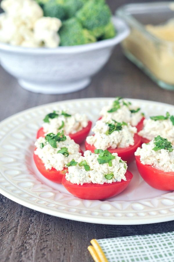 Vegan Stuffed Tomatoes - tomato halves filled with ricotta cheese, topped with chopped basil, on a white plate 